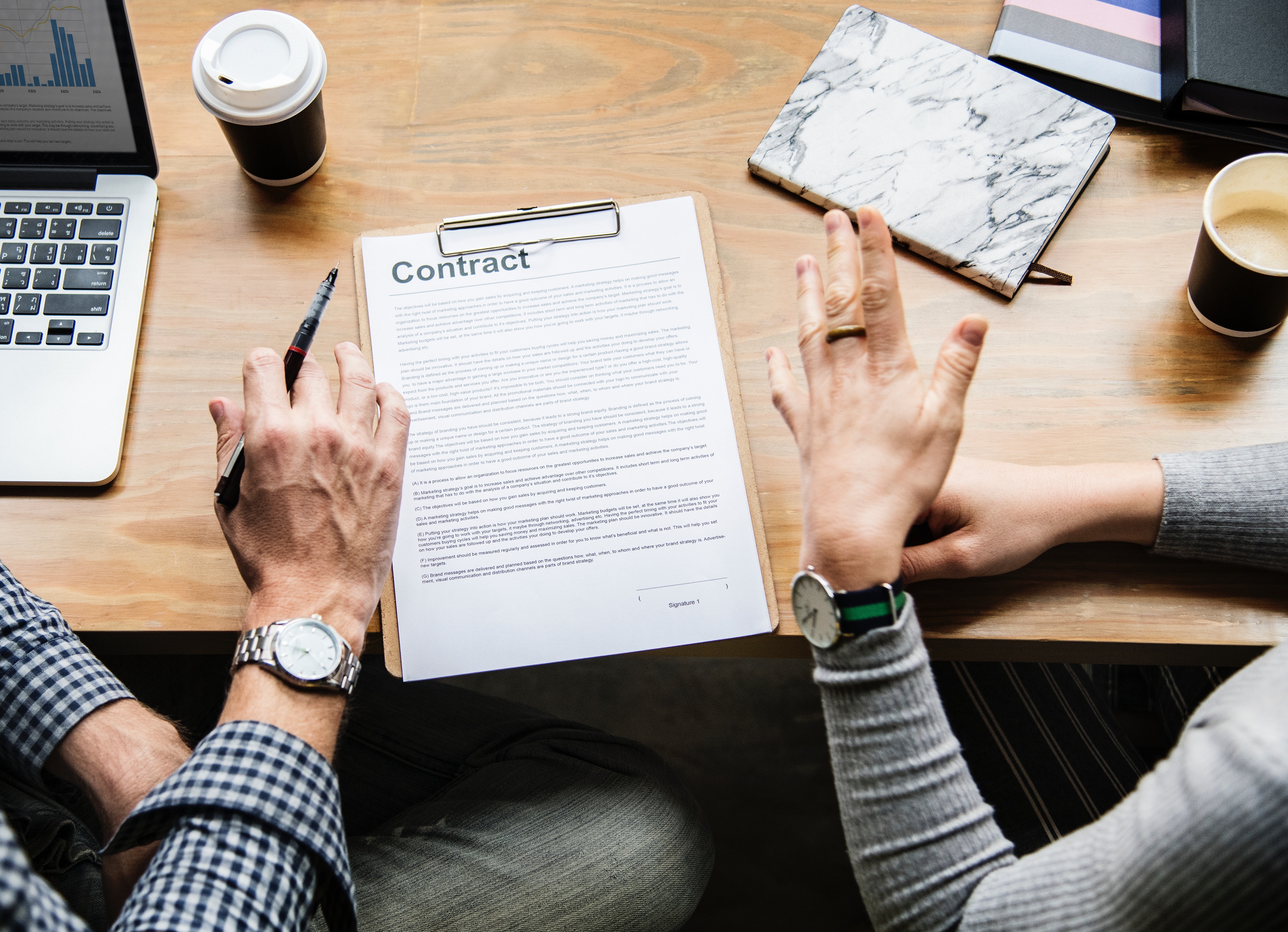 two people signing a contract